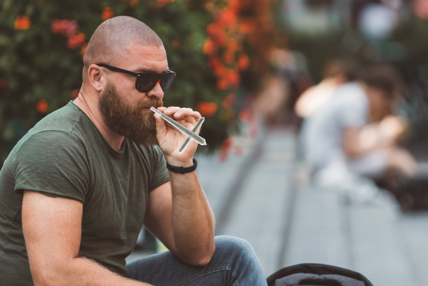A man sits in a park about to enjoy a cross joint