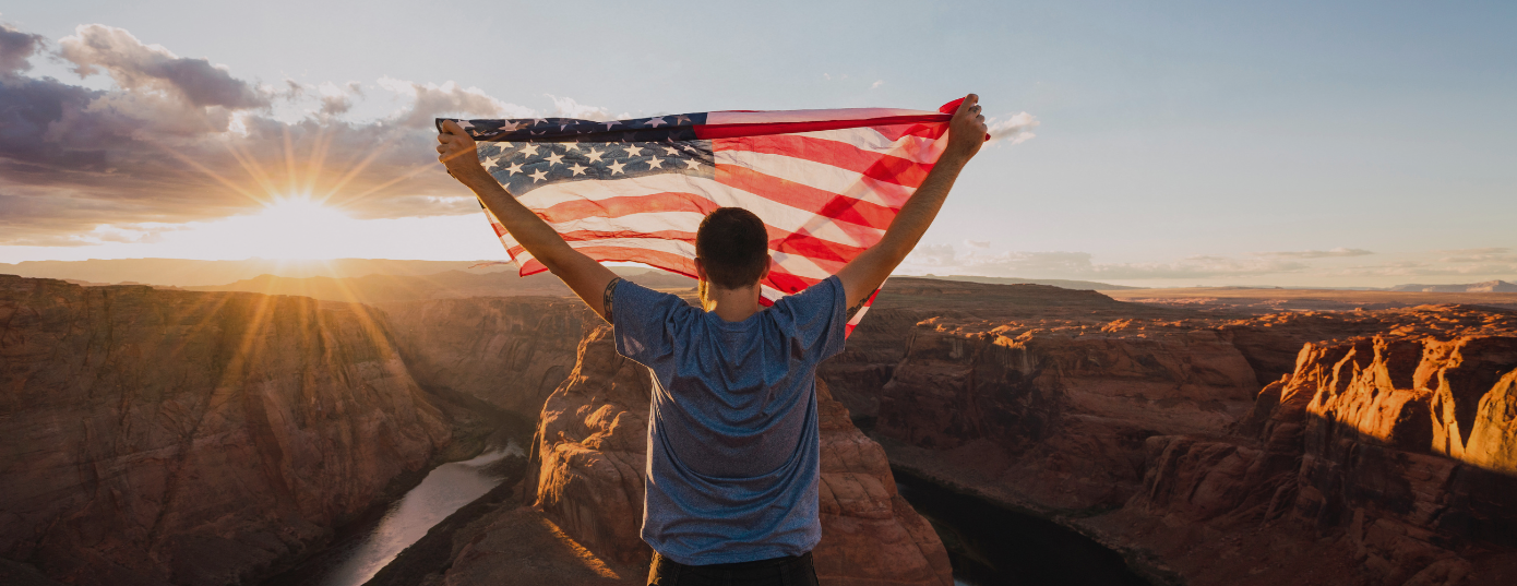 man holding US flag in Grand Canyon