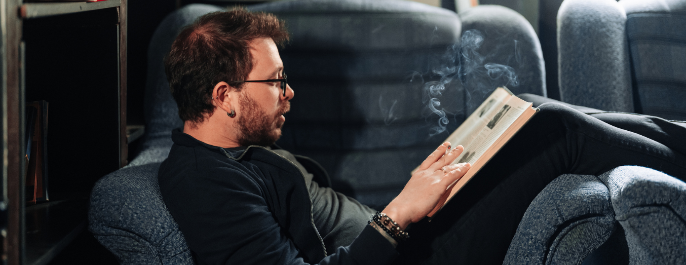 man reading a book and smoking in a couch