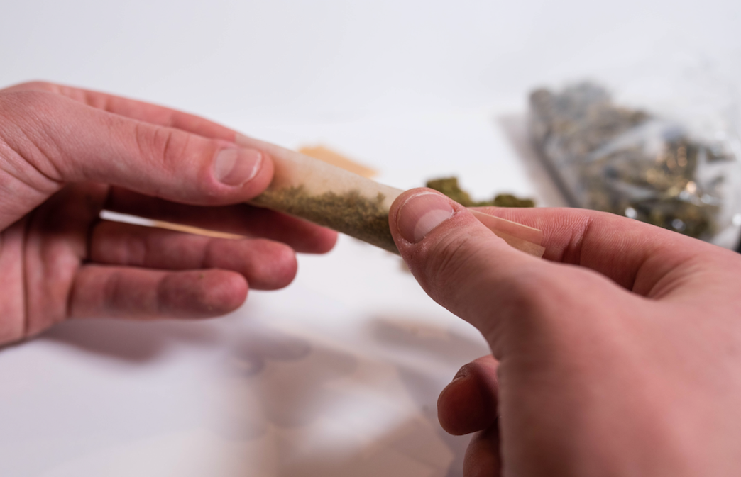 fingers rolling a joint with hemp paper