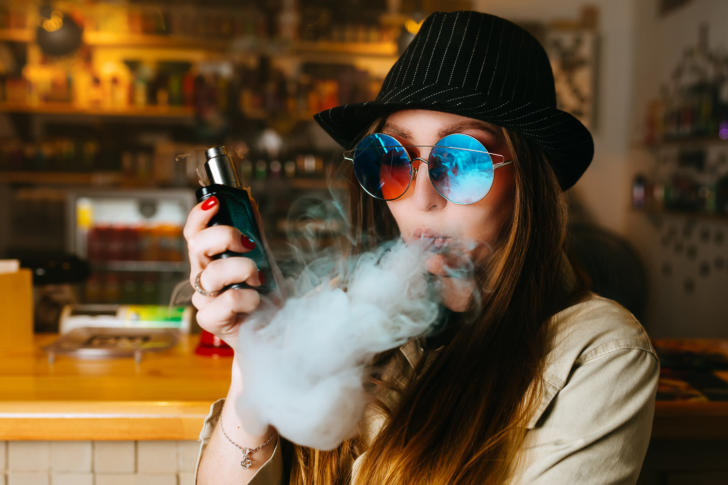fille vaping avec chapeau et lunettes de soleil