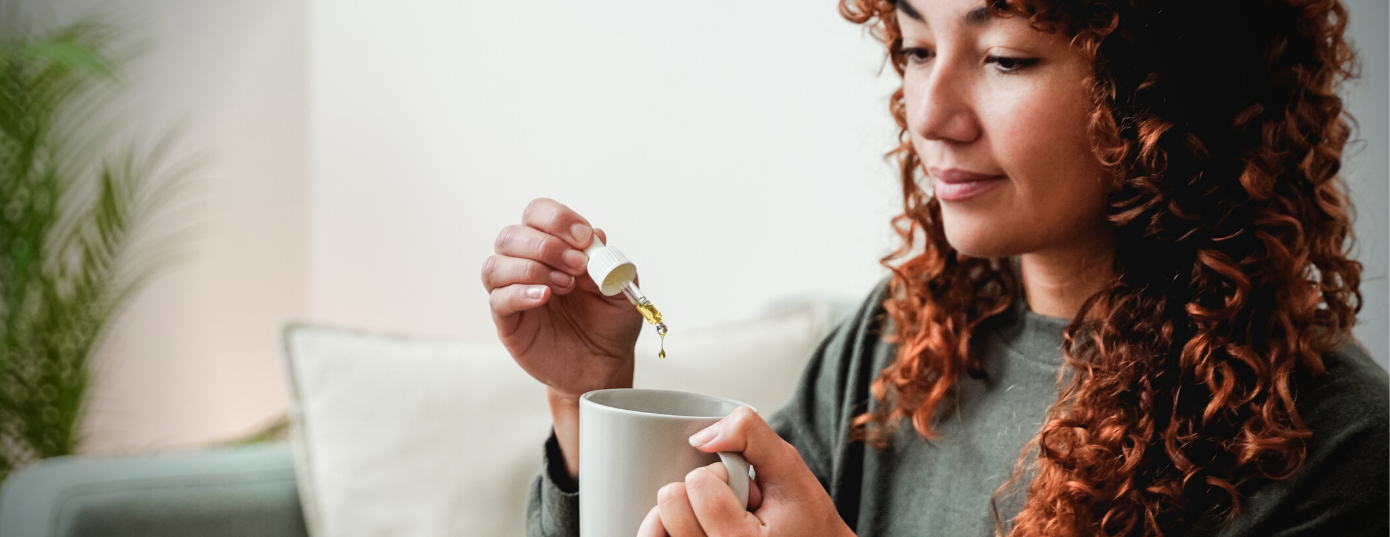 woman taking CBD oil in a cup