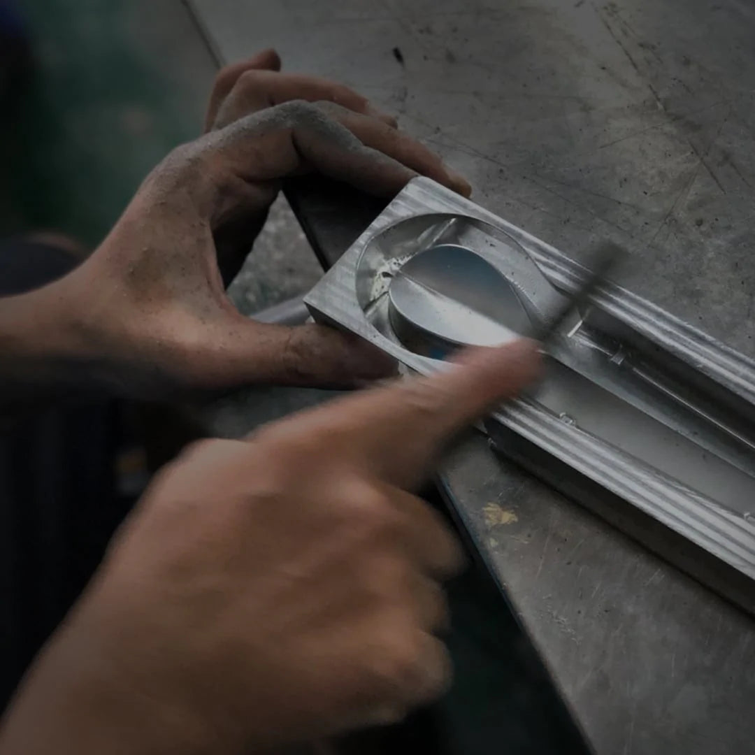 worker's hand holding a silver aluminum mold of KOL pipe