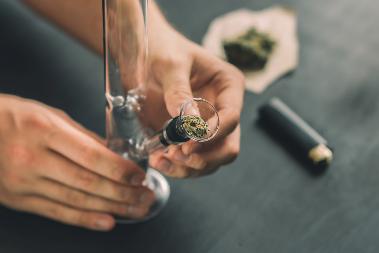 Une personne met du cannabis dans une pipe à bulles