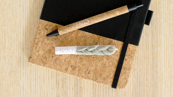 A perfectly roller braided joint sits on top of a journal beside a pen