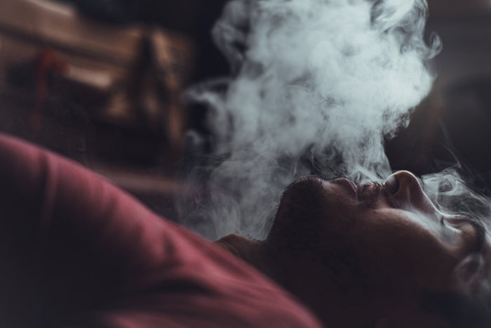 Ein Mann lächelt, während er eine Wolke von verdampftem Cannabis aus seinem Volcano Vaporizer ausatmet