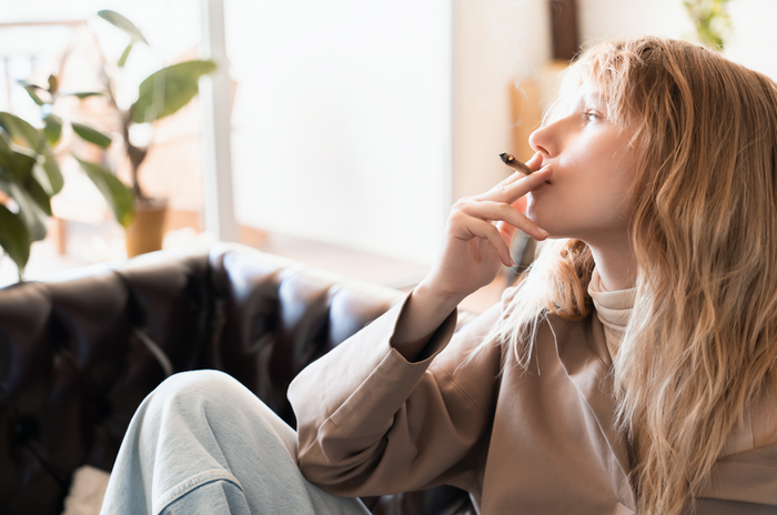 Blonde woman smoking weed inside her house on the couch