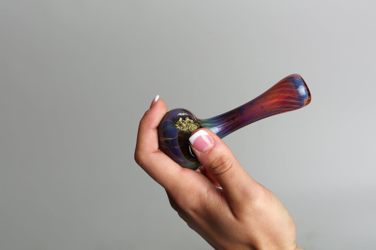 A woman holds a glass pipe up against a clean white background wondering Can you Clean a Pipe With Hydrogen Peroxide?