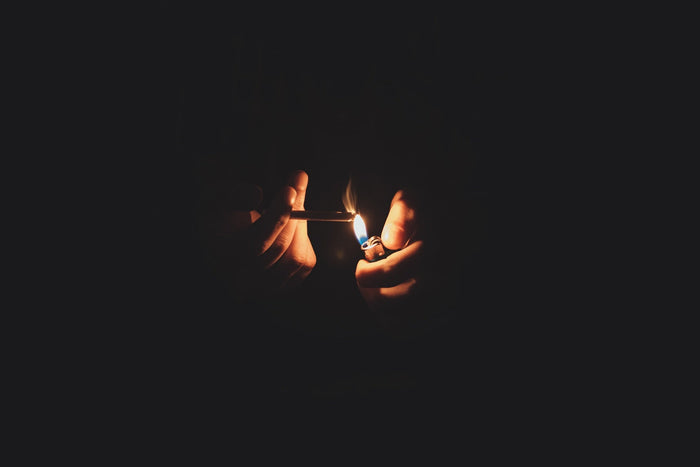 Man holding holding a clipper lighter while lighting a joint 