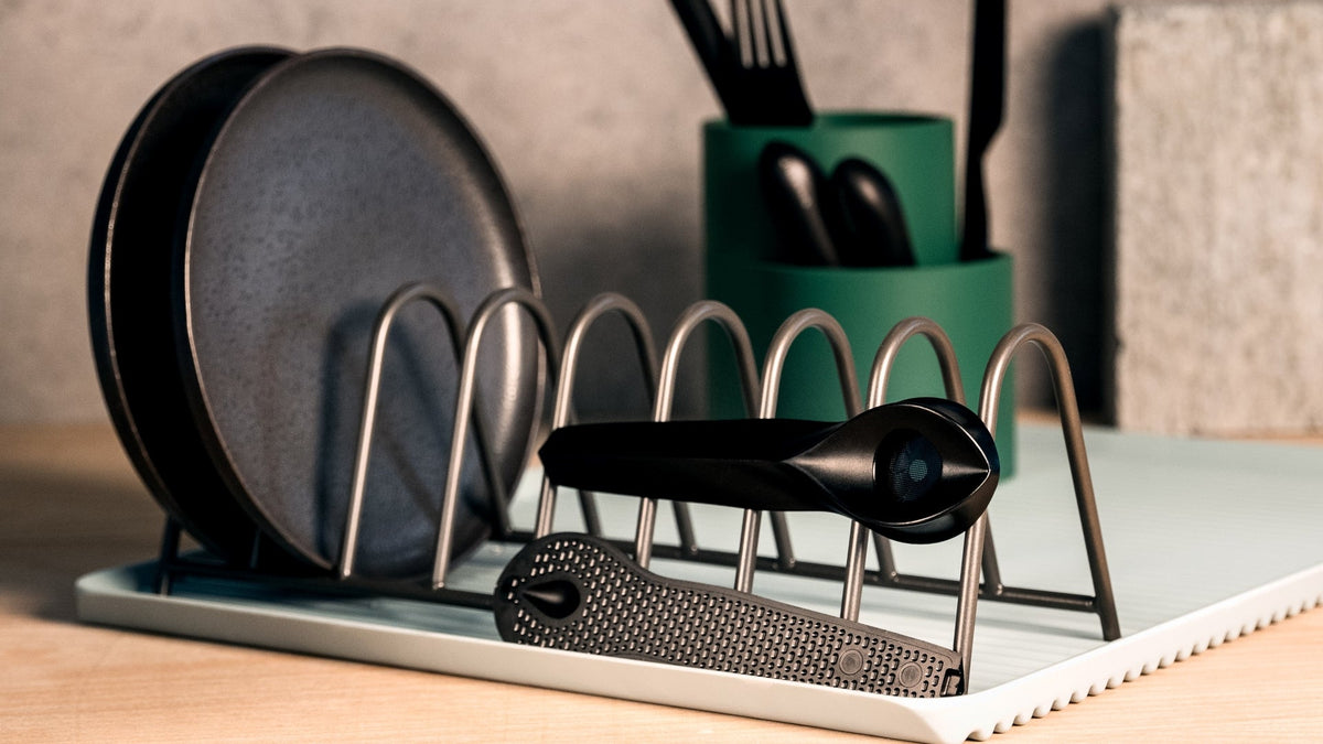 A clean black weed pipe sits on a dish rack drying. 