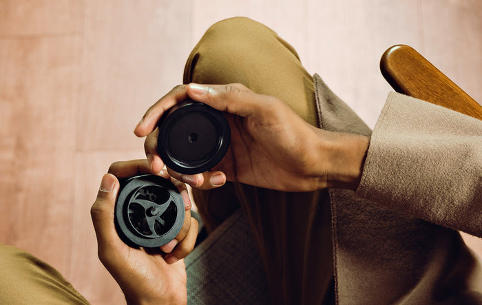 A man holds a black KLIP weed grinder in his lap wondering 