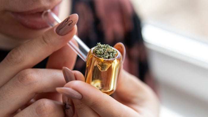 A woman smokes weed from a glass pipe. It is packed to the brim with green cannabis