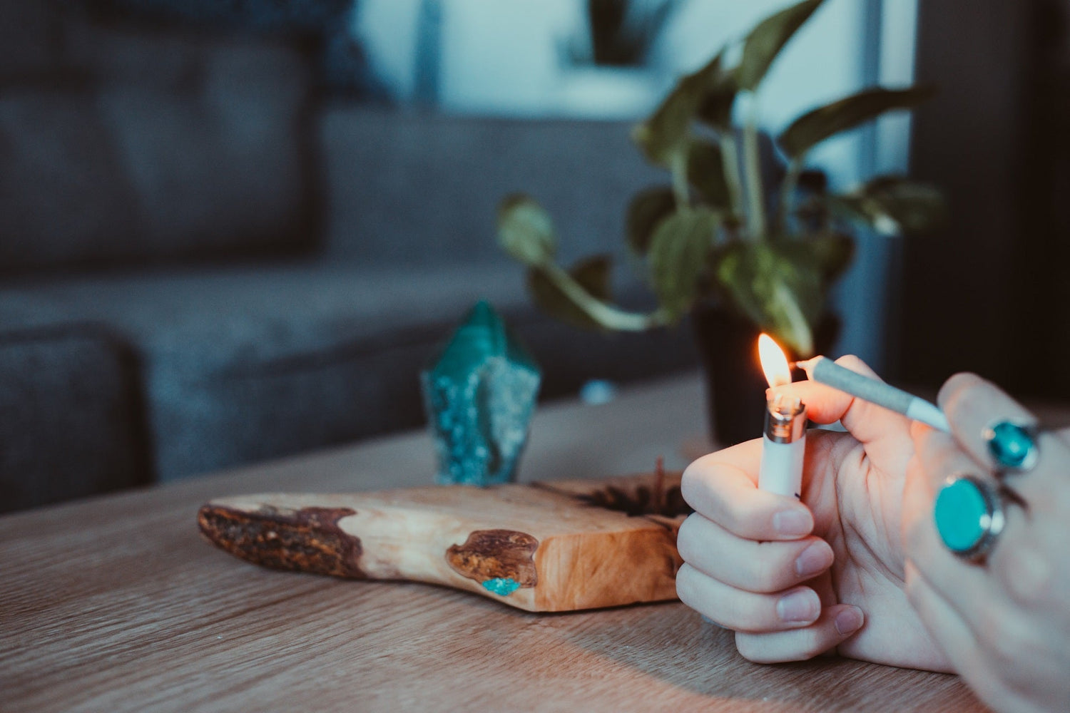 A person holds a lighter in the right hand while burning the tip of a joint in the left hand.