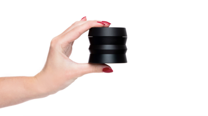 hand with red nail polish holding a black weed grinder in white background