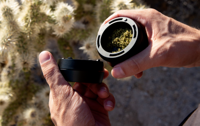 Hands holding KLIP grinder with grounded weed on it