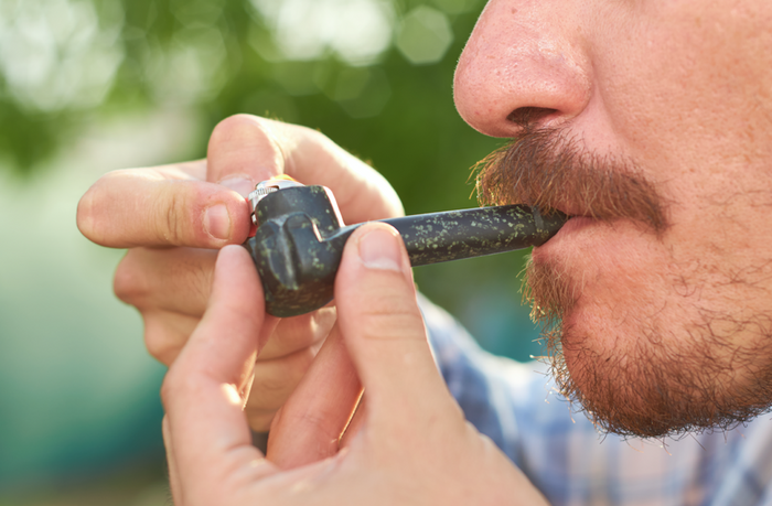 Hombre fumando hierba en pipa