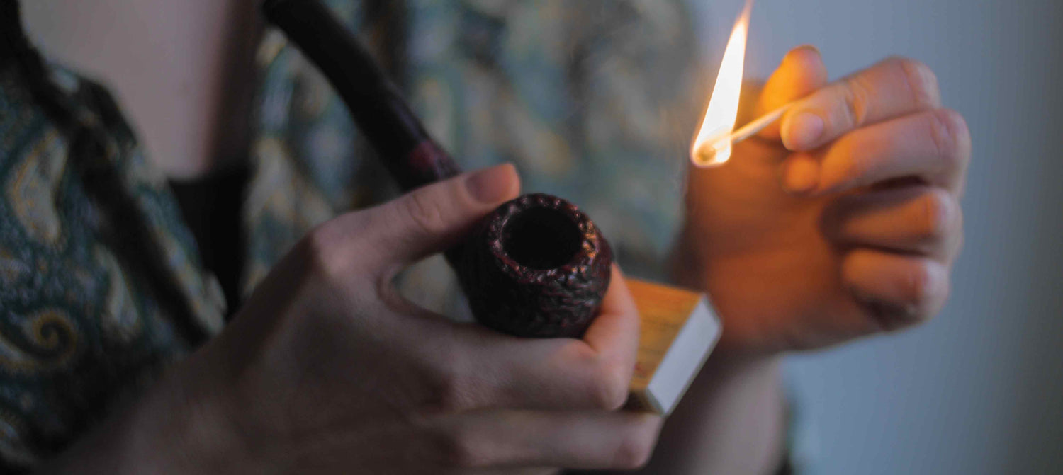 Close up shot of someones hands lighting a tobacco pipe