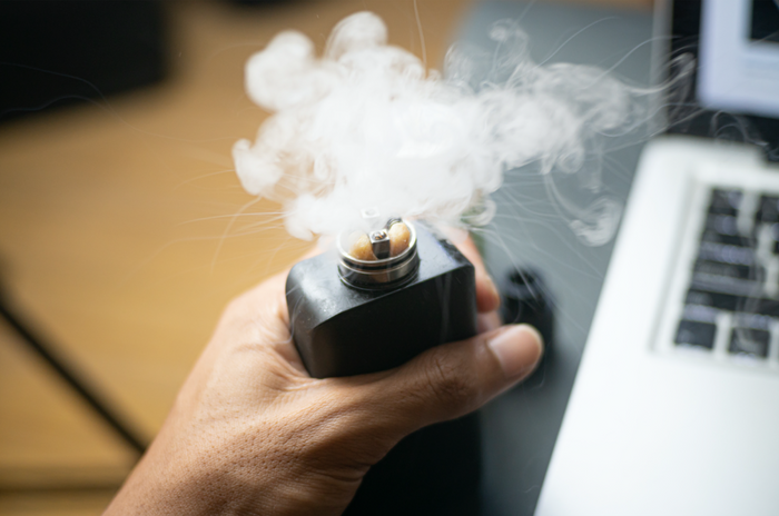 hand holding premium vape with vapor