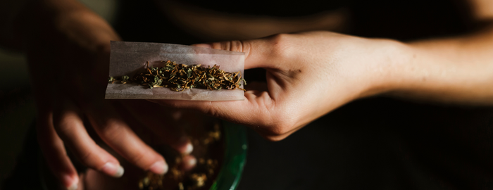 mains d'une personne roulant un joint