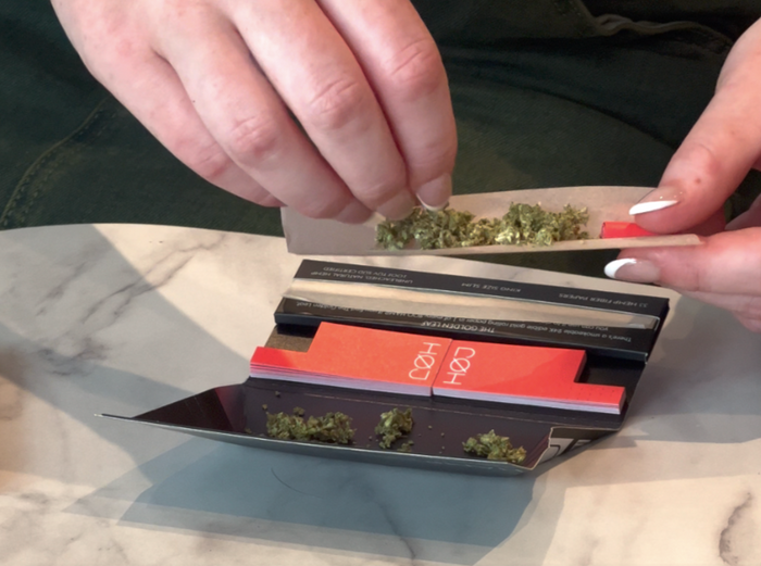 pouring weed from a grinder to a large size rolling paper