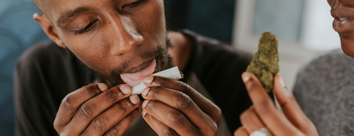 black man rolling a weed joint and a cannabis bud in hand