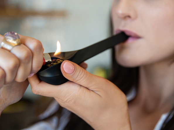 woman smoking from a weed pipe with cannabis
