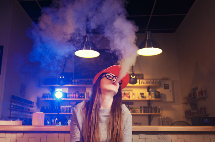 woman smoking from a vape in smoke shop